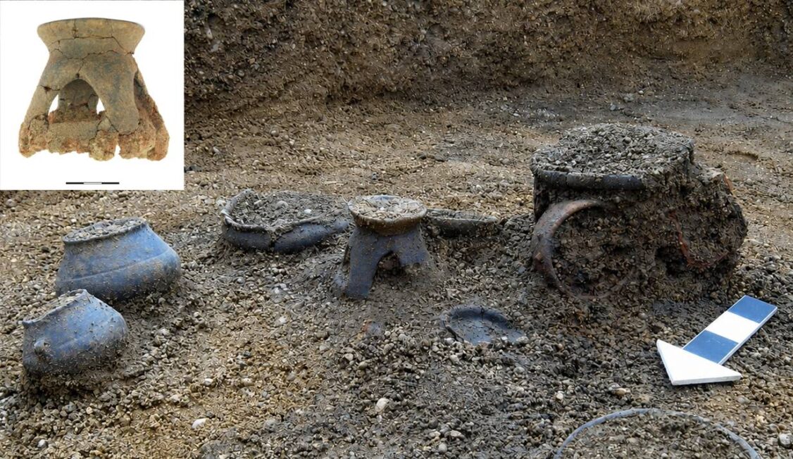 Kilka naczyń ceramicznych odsłoniętych w ziemi na stanowisku archeologicznym.