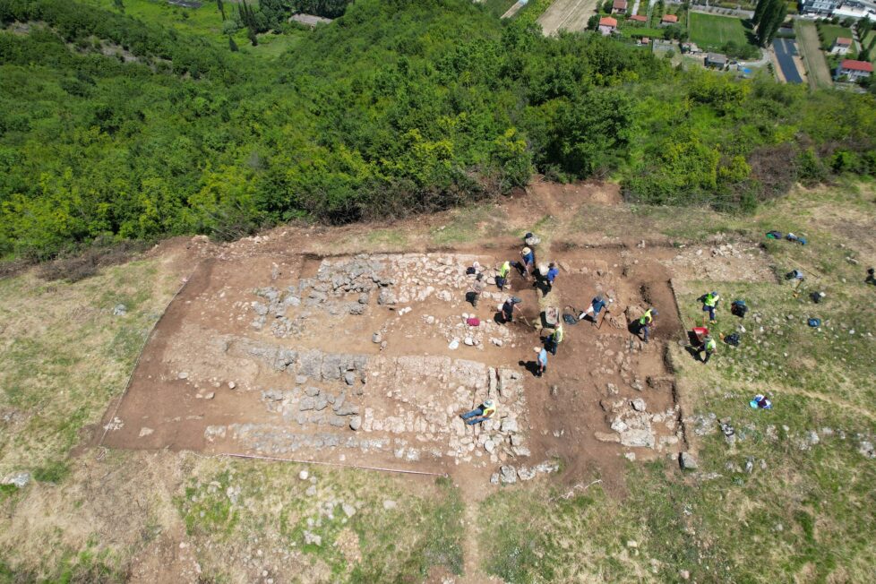 Widok z drona na archeologów pracujących przy kamiennych fundamentach na wzgórzu w Bushat w północnej Albanii.