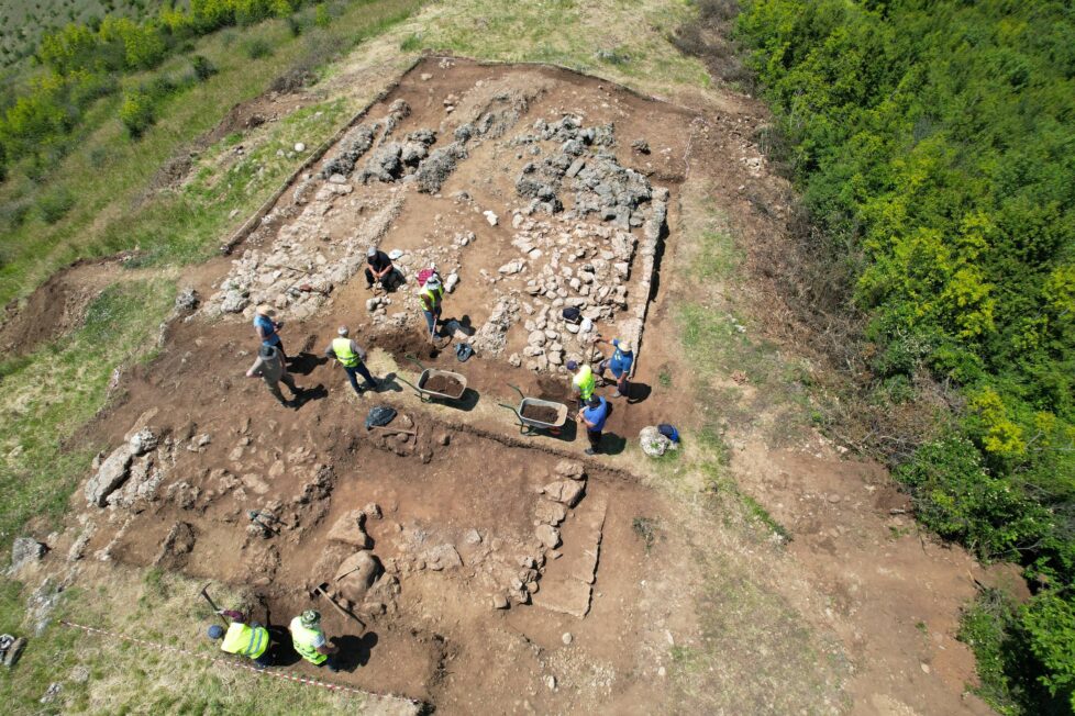 Archeolodzy pracujący w wykopie z kamiennymi fundamentami budowli na stanowisku Bushat.