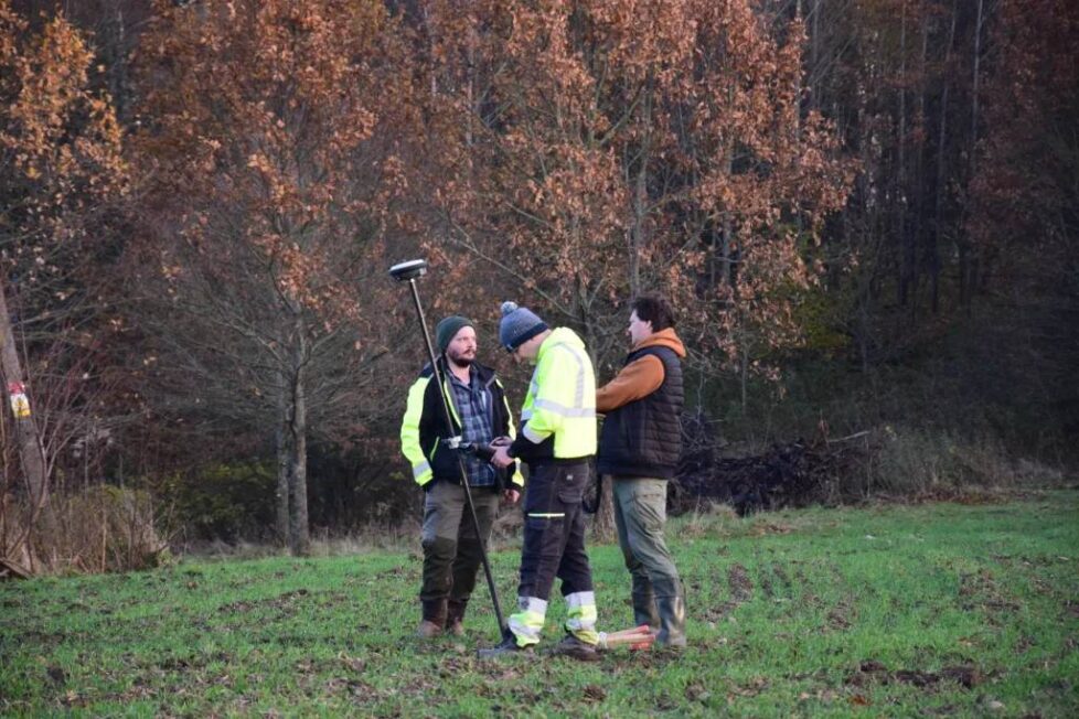 Archeolodzy wykonują pomiary geodezyjne na stanowisku w terenie leśnym