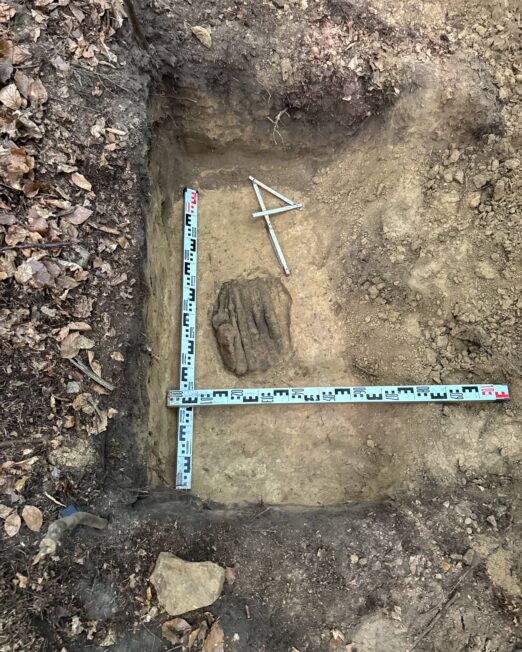 Grzywny siekieropodobne i żelazne narzędzia odsłonięte w wykopie archeologicznym pod Bochnią, obok rozłożona miarka