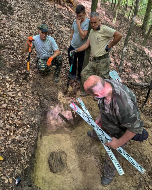 Zespół wraz z archeologami w leśnym wykopie podczas odsłaniania depozytu wczesnośredniowiecznych przedmiotów żelaznych pod Bochnią