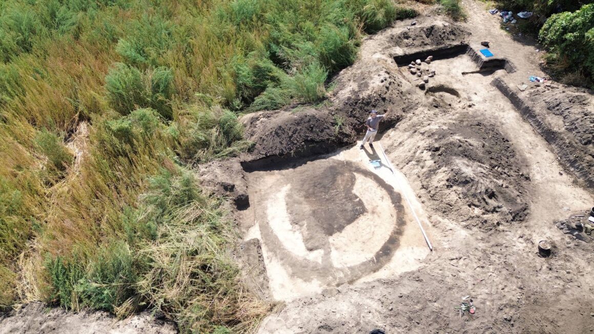 Widok z drona na kolisty zarys kurhanu kultury ceramiki sznurowej widoczny w wykopie archeologicznym