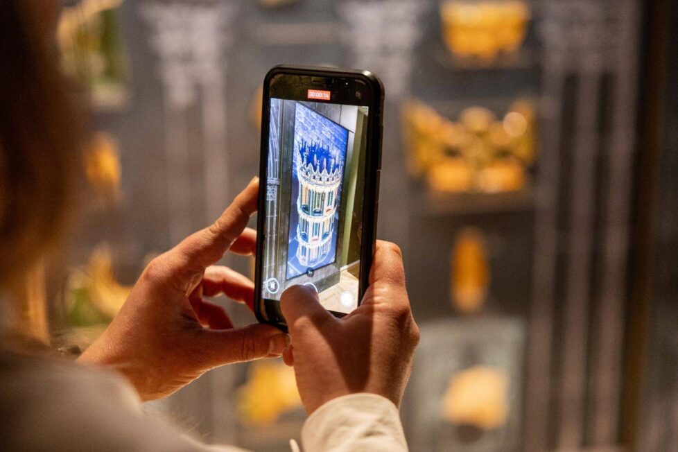 Zwiedzający ogląda rekonstrukcję 3D pieca kaflowego w Muzeum Śląska Opolskiego na smartfonie.