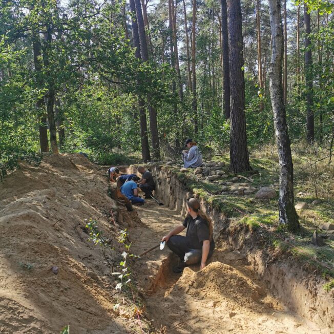Archeolodzy pracują w wykopie przecinającym grobowiec neolityczny na zalesionym stanowisku w Sobocie.